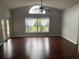 An open living room featuring hardwood floors and a large window overlooking the front yard at 527 Buckhaven Loop, Ocoee, FL 34761