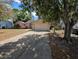 View of a single-story home, including front yard, driveway, and some mature trees at 8040 Equitation Ct, Orlando, FL 32818