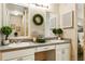 This bathroom boasts double sinks, decorative mirrors, and neutral tile flooring at 1000 Winderley Pl # 237, Maitland, FL 32751