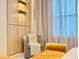 Bedroom sitting area features a gray chair, soft, blanket, yellow ottoman and natural light from the window at 10012 Voyager Way, Orlando, FL 32821