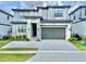 Modern two-story home featuring a gray brick driveway, lush landscaping, and an attached two-car garage at 10012 Voyager Way, Orlando, FL 32821