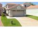 Two-story home featuring an attached two car garage, concrete driveway, and well manicured lawn at 1009 Troon Trce, Winter Springs, FL 32708