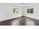 Bright, minimalist bedroom with two large windows and dark wood-style floors at 1071 Sweet Tree Ct, Apopka, FL 32712