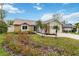 A quaint brick home, accented by a lush lawn, colorful flowers and mature palm trees at 1071 Sweet Tree Ct, Apopka, FL 32712