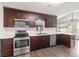 Well-lit kitchen showcasing stainless steel appliances, granite countertops, and dark wood cabinets at 1071 Sweet Tree Ct, Apopka, FL 32712