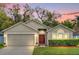 Charming single-story home featuring a well-maintained lawn, two car garage, and inviting front entrance with a red door at 137 Golfside Cir, Sanford, FL 32773