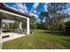 A home's expansive backyard showcases a covered patio, green grass, and a black fence at 17216 Goldcrest Loop, Clermont, FL 34714