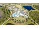 Aerial view of a beautiful community pool area with palm trees, landscaping, and lake views at 17216 Goldcrest Loop, Clermont, FL 34714