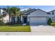 Charming single-story home with lush landscaping, palm trees and a two-car garage at 17216 Goldcrest Loop, Clermont, FL 34714