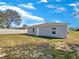 A simple backyard features a gray exterior, grassy area with a white fence surrounding the property at 209 Fig Ct, Kissimmee, FL 34759