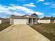 A single story house features a two-car garage, a welcoming front porch, and a pristine white fence at 209 Fig Ct, Kissimmee, FL 34759