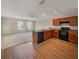 Eat-in kitchen boasting wood cabinets, sleek black appliances, and attractive wood-look floors with a view to the living area at 209 Fig Ct, Kissimmee, FL 34759