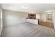 Open-concept living room with neutral walls and plush gray carpeting adjacent to kitchen with breakfast bar at 209 Fig Ct, Kissimmee, FL 34759