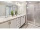 Modern bathroom showcasing double sinks, white cabinetry, and a glass-enclosed shower at 5996 Wildflower Field Way, St Cloud, FL 34771