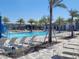 Community pool featuring plenty of lounge chairs, palm trees, and a splashpad water feature on a bright sunny day at 5996 Wildflower Field Way, St Cloud, FL 34771