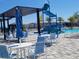 Inviting community pool area with tables, chairs, umbrellas, a splashpad, and a shallow area for children at 5996 Wildflower Field Way, St Cloud, FL 34771