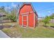 Red barn-style shed in backyard with a concrete block foundation, a yard, and privacy fence at 6373 Forecastle Ct, Orlando, FL 32807