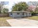 Charming single-story house, showcasing a gray brick exterior, a simple carport, and a spacious concrete driveway at 1205 Flewelling Ave, Ocoee, FL 34761