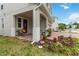 Inviting front porch features seating, flowerpots, and brick paving leading to a charming front door and colorful flowerbeds at 1212 Bear Oak Ln, Deland, FL 32720