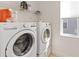 Bright laundry room featuring a modern, front-loading washer and dryer set, and handy overhead shelving for storage at 1212 Bear Oak Ln, Deland, FL 32720
