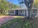 Charming single-story home with a gray exterior, red driveway, and a lush, mature tree in the front yard at 1219 Dewey Ave, Orlando, FL 32808