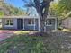 This charming single-story home has a welcoming covered entrance and large tree at 1219 Dewey Ave, Orlando, FL 32808