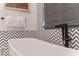 Close up of a modern free standing bathtub with chevron patterned tile wall and a black faucet at 1297 Grand Traverse Pkwy, Reunion, FL 34747