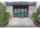 Grand front entrance with a contemporary glass door, stone facade, and meticulously maintained landscaping at 1297 Grand Traverse Pkwy, Reunion, FL 34747