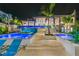 Backyard oasis with a two-tiered pool, cascading water feature, and an illuminated outdoor space at 1297 Grand Traverse Pkwy, Reunion, FL 34747