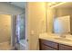 Bright bathroom featuring a single sink vanity, a large mirror, and a shower-tub combo at 14031 Jomatt Loop, Winter Garden, FL 34787