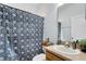 Cozy bathroom featuring a shower with patterned curtain, a sink with a mirror, and a wooden accent shelf at 150 Magnolia Park Trl, Sanford, FL 32773