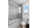 Bathroom with a tiled shower-tub combination, a toilet, and wood-look flooring, plus a window at 207 Polermo Ave, St Cloud, FL 34771