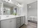 Bright bathroom featuring double sinks, white countertops, gray cabinetry, and a glass-enclosed shower at 207 Polermo Ave, St Cloud, FL 34771