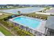 Aerial view of a community pool with lounge chairs, lush landscaping, and lakeside view at 207 Polermo Ave, St Cloud, FL 34771