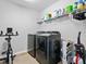 Organized laundry room featuring gray front load washer and dryer, storage shelf, and stationary exercise bike at 207 Polermo Ave, St Cloud, FL 34771