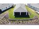 Aerial view of a backyard featuring a covered patio, a well-maintained lawn, and flower beds surrounded by a black fence at 2842 Purple Meadow Ct, Minneola, FL 34715