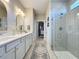 Modern bathroom with double sinks, tiled walk-in shower, gold fixtures, and a view of the walk-in closet at 2842 Purple Meadow Ct, Minneola, FL 34715