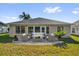 Back exterior view featuring a patio with elegant outdoor seating and lush green lawn at 346 Vista Oaks Way, Davenport, FL 33837