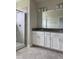 Bright bathroom featuring a glass-enclosed shower and a vanity with dual sinks and gray countertop at 4724 Tribute Trl, Kissimmee, FL 34746