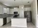 Modern kitchen featuring white cabinets, gray countertops, stainless steel appliances, and a center island at 4724 Tribute Trl, Kissimmee, FL 34746