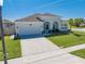 Charming one-story home featuring arched entryway, lush lawn, and attached two-car garage at 5301 Amersham Ln, St Cloud, FL 34771