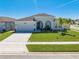 Charming one-story home featuring arched entryway, lush lawn, and attached two-car garage at 5301 Amersham Ln, St Cloud, FL 34771