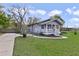 Quaint gray home with a cozy front porch, green lawn and a long driveway at 5990 Hibiscus Rd, Orlando, FL 32807