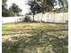 Overgrown yard featuring a white wooden fence and mature trees at 7018 Stockholm Way, Orlando, FL 32822