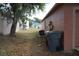 View of the backyard and side of house with trash bins and lush tree providing shade at 721 Waxwing Ct, Kissimmee, FL 34759