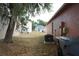 View of the backyard and side of house with trash bins and lush tree providing shade at 721 Waxwing Ct, Kissimmee, FL 34759