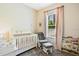 Cozy Bedroom with a white crib, glider chair, and soft pink accents near a sunlit window at 806 Roswell Cv, Lake Mary, FL 32746