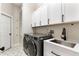 Well-lit laundry room with white cabinets, gray washer and dryer, and stylish tile flooring at 806 Roswell Cv, Lake Mary, FL 32746