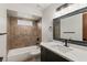 Bathroom features a tub, a decorative mirror, and dark fixtures against patterned tile at 9360 Sonia St, Orlando, FL 32825