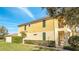 A yellow two-story home with green shutters, lush landscaping, and a gated entrance at 12016 Lorenza Ln, Orlando, FL 32827